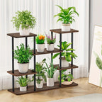 4-tier black metal and wood plant stand holding multiple green plants in a bright living room setting.
