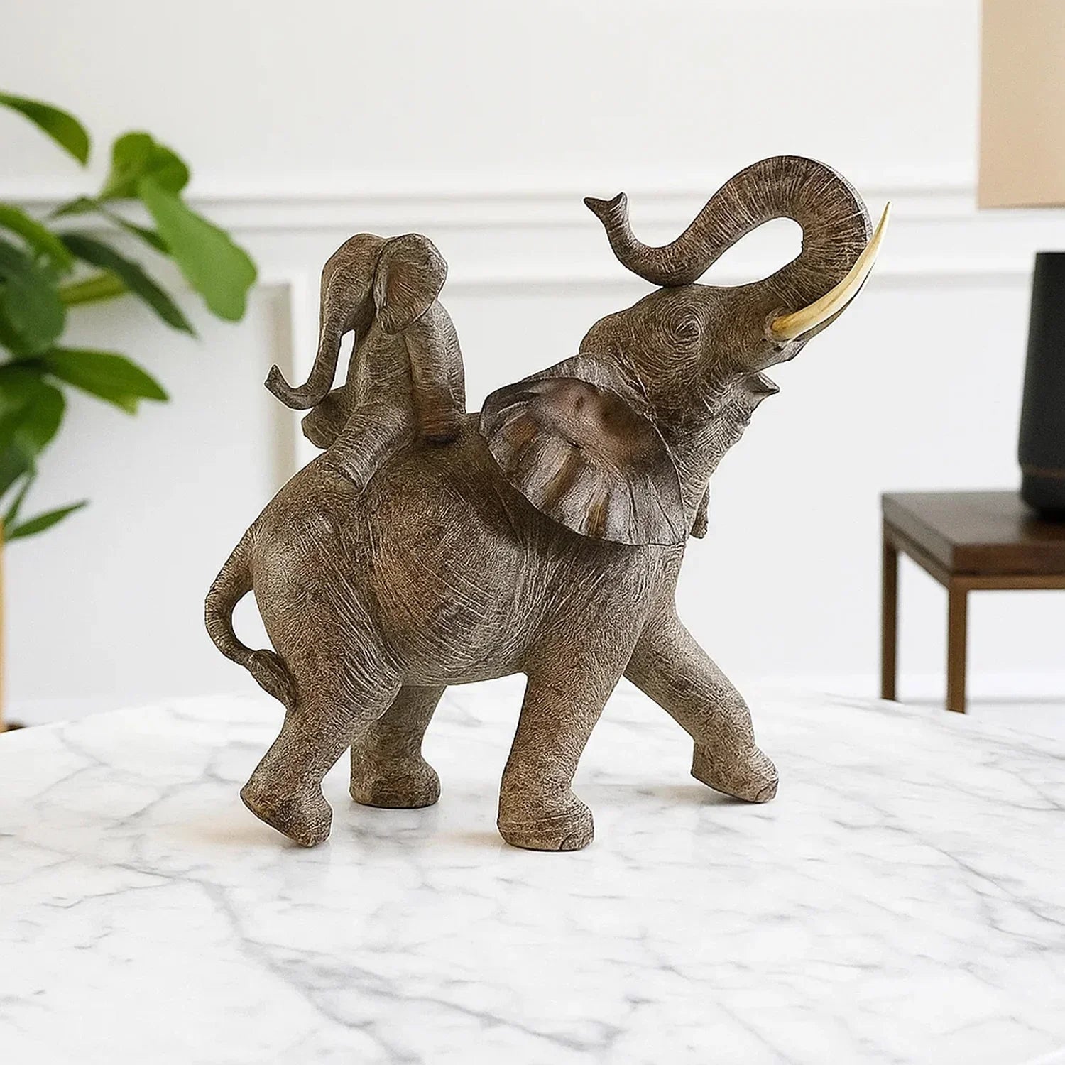 Large textured African elephant statue with a calf on its back, featuring earthy tones and a raised trunk.