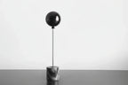 Decorative object with a black sphere and marble base on a white background
