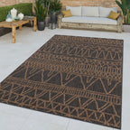 Charcoal and tan modern ethnic pattern indoor outdoor rug on a patio with outdoor furniture.