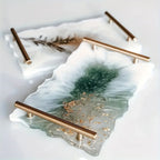 Two decorative trays with gold handles on a light background