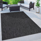 Mottled anthracite outdoor rug on a modern patio with dark furniture and a fire pit table.