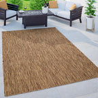 Mottled brown and beige weatherproof outdoor rug on a patio with modern outdoor furniture and a fire pit.