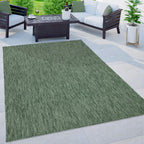 Mottled dark green outdoor rug on a modern patio with white sofas and a fire pit table