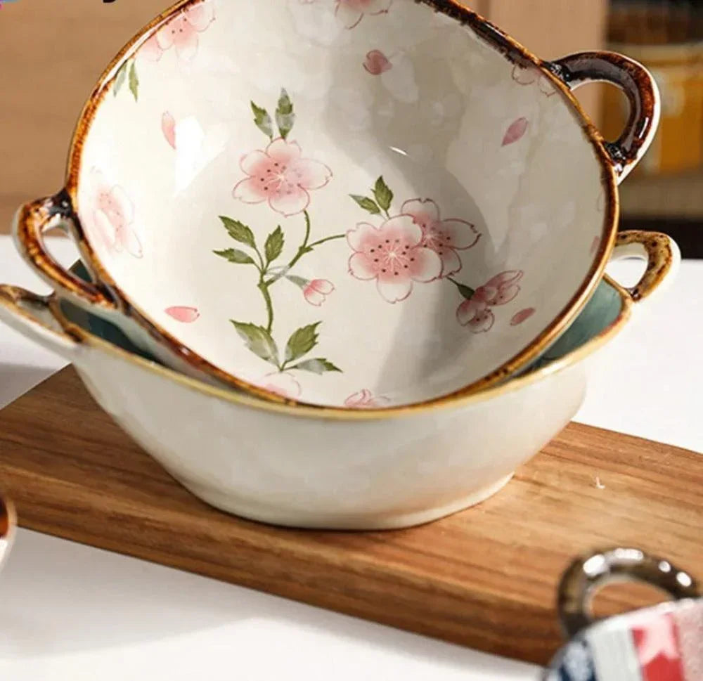 White ceramic noodle bowl with pink cherry blossom patterns and brown handles enhances dining experience and table settings