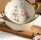 White ceramic noodle bowl with pink cherry blossom patterns and brown handles enhances dining experience and table settings