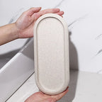 Neutral tone oval bathroom vanity tray with a textured surface and striped rim.