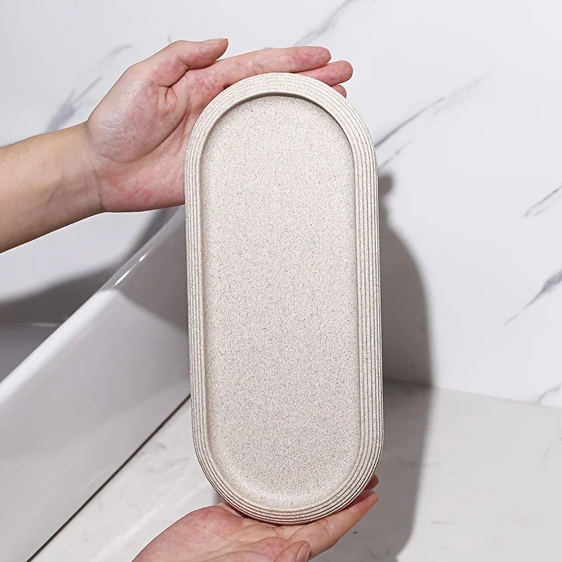 Neutral tone oval bathroom vanity tray with a textured surface and striped rim.