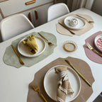 Dining table set with plates, napkins, and cutlery on placemats.