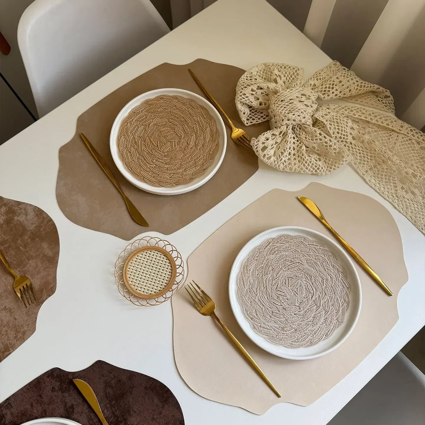 Dining table setting with plates, cutlery, and placemats on a white table.