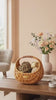 Handwoven rattan storage basket with decorative balls styled next to white ceramic vase with pink and peach flowers - House of Avana home decor