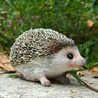 Realistic resin hedgehog figurine with detailed brown and white fur texture sitting on a stone in a garden.