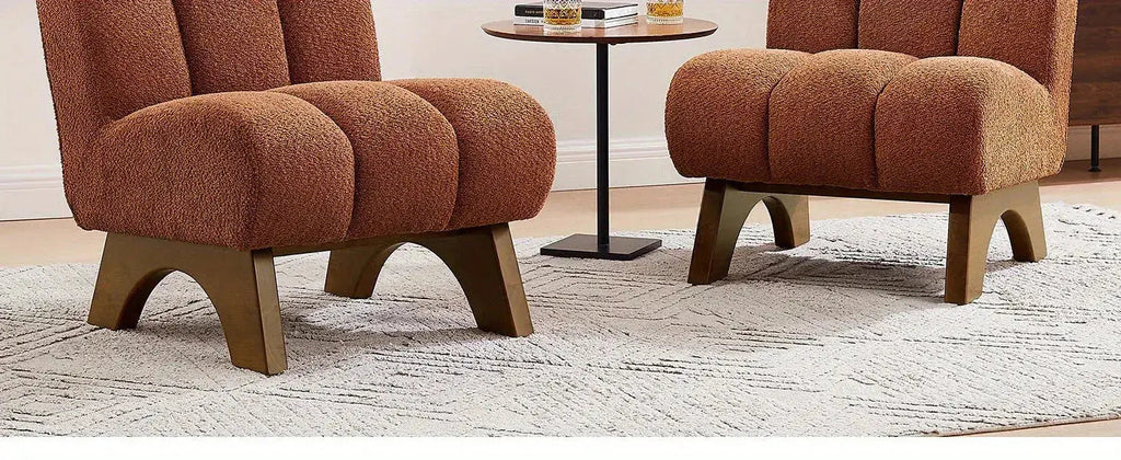Two terracotta upholstered chairs with arched wooden legs on a light-colored textured rug.