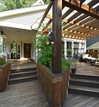 Outdoor patio with wooden pergola, plants, and a decorative parrot on a柱子