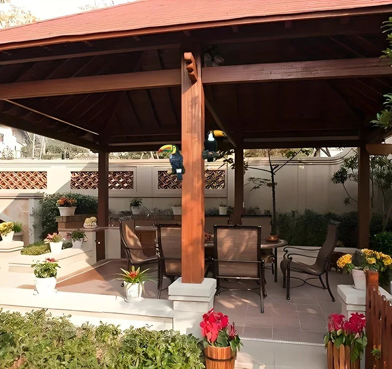 Outdoor patio area with wooden pergola, tables, chairs, and decorative plants.