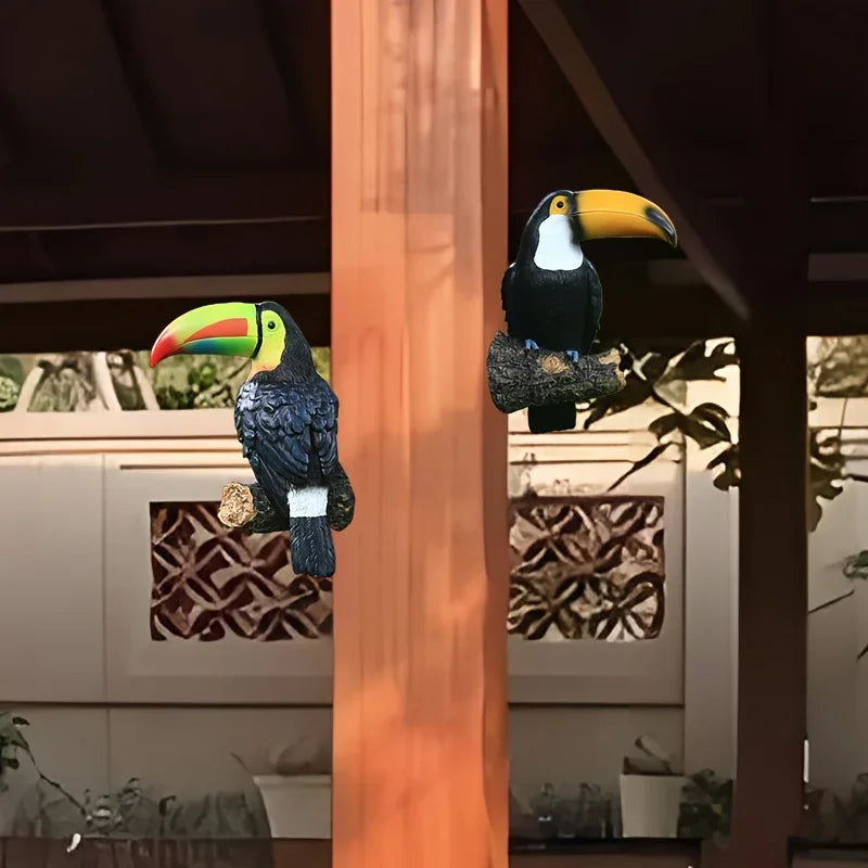 Two toucan bird figurines on a wooden post with a blurred background