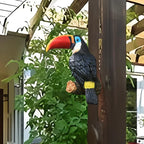 Decorative toucan bird figure on a branch with green foliage in the background