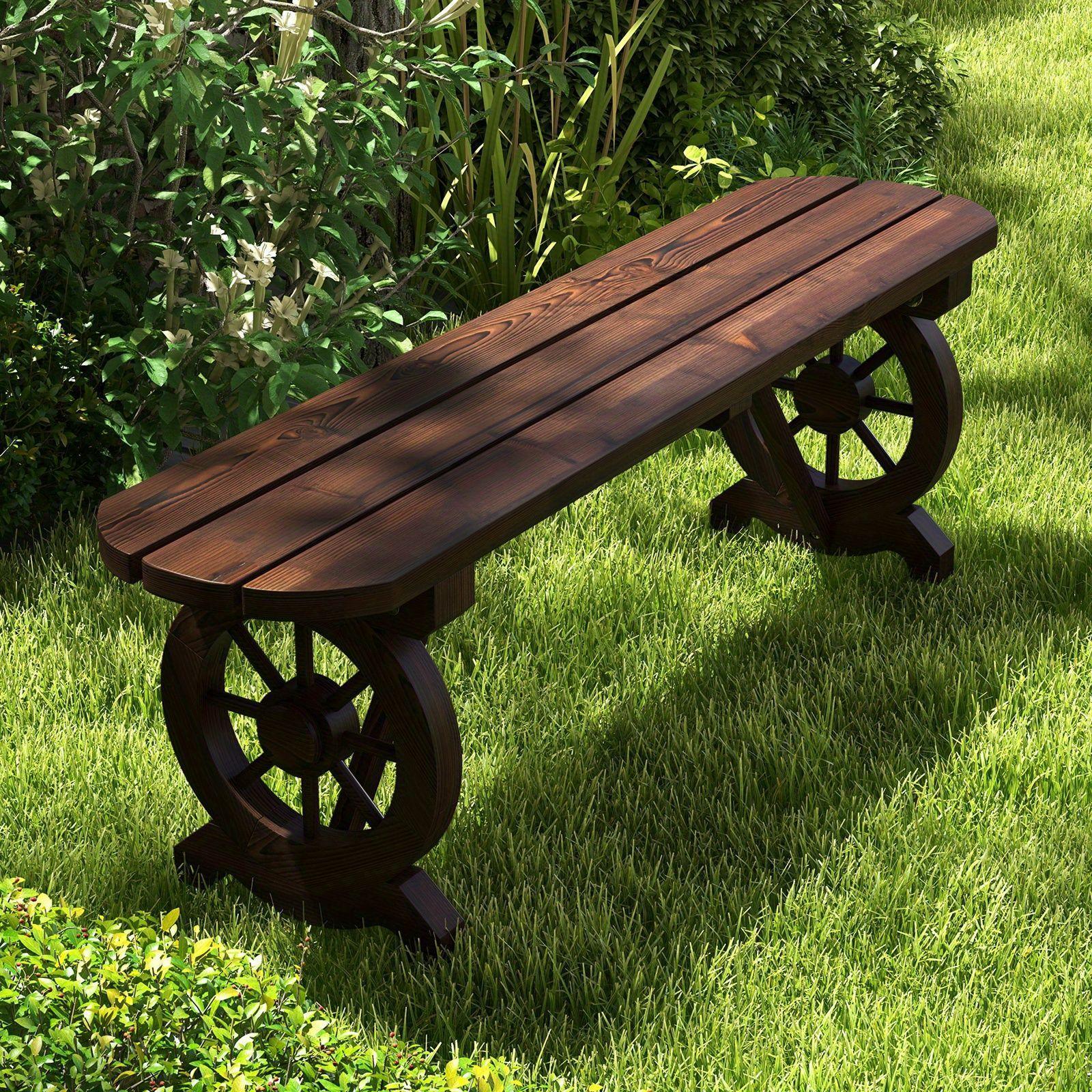 Rustic carbonized fir wood bench with wagon wheel legs placed on a lush green lawn.