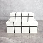 Stacked white textured boxes with black geometric accents complement a modern matte black thinker sculpture figurine