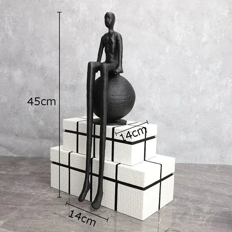 Modern matte black thinker sculpture featuring a black matte-finished abstract figurine with elongated limbs on a textured sphere