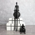 Abstract long-legged thinker sculpture featuring a modern matte black finish on a seated figure atop a spherical base