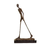 Bronze-colored abstract walking man sculpture with textured metal finish on dark base modern figurine decor