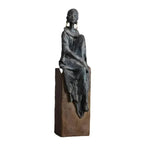 Bronze-colored african women sculpture figurine of seated woman with draped fabric and hoop earrings on wooden base
