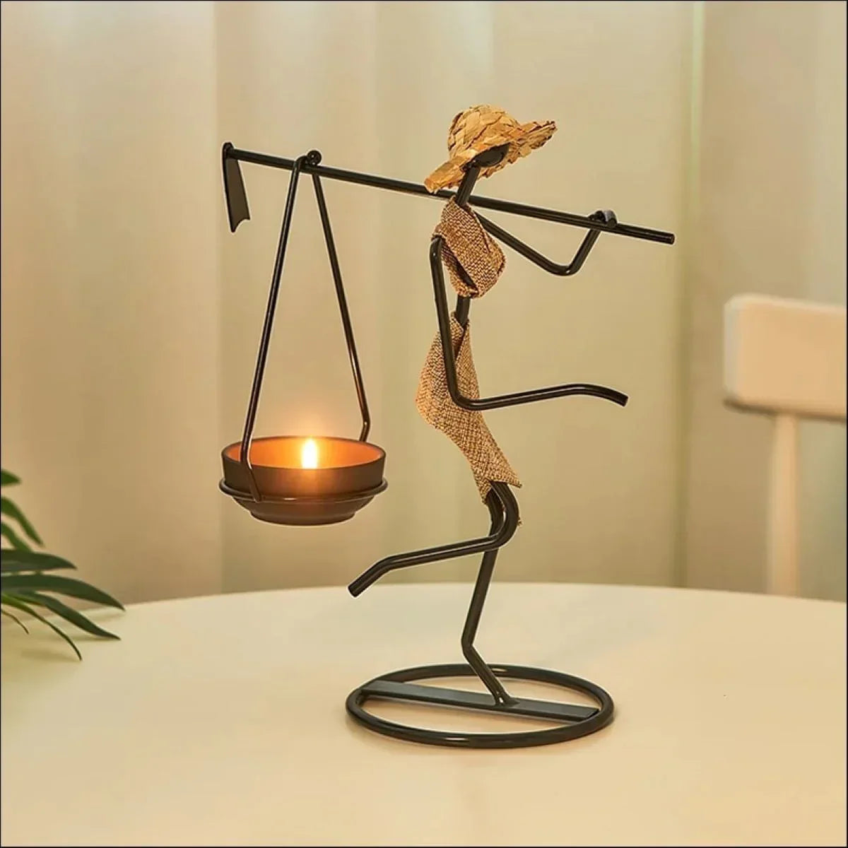 Black metal candle holder figurine with gold woven fabric carrying a candle lantern for warm home decor ambiance