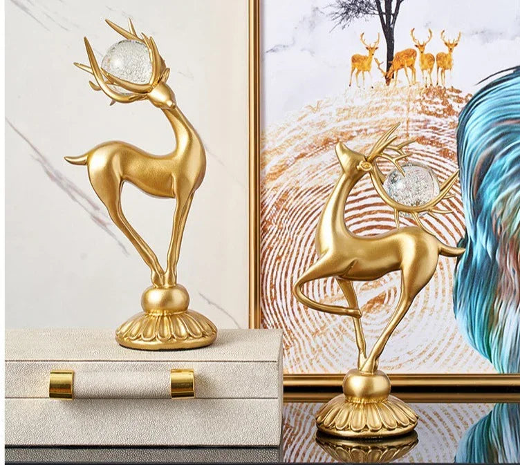 Golden deer figurine with antlers holding a clear crystal orb featuring crystal floral accents in a decorative set