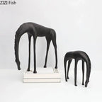 Modern minimalist black matte-finished abstract giraffe figurines with bowed necks complement minimalist black horse sculpture decor