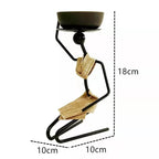 Black metal candle holder shaped like a stylized human figure with gold burlap accents for decorative stick home decor